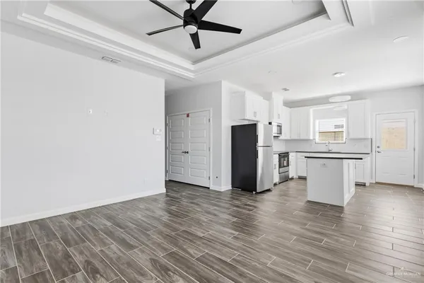a view of a kitchen with stainless steel appliances wooden floor and a refrigerator