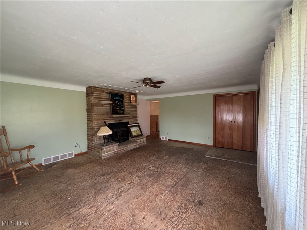 4912 Hillside Road Independence, OH 44131 - Photo 4 of 20 Unfurnished living room featuring dark wood-style flooring, a fireplace, a ceiling fan, and a textured ceiling