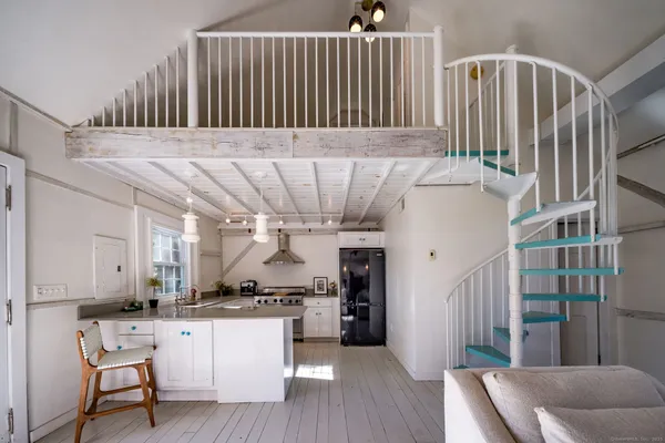 a kitchen with stainless steel appliances kitchen island granite countertop a refrigerator a stove a sink dishwasher and white cabinets with wooden floor