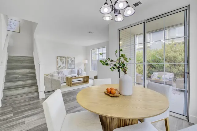 a dining room with wooden floor a chandelier a glass table and chairs