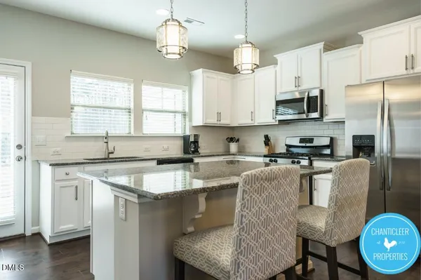 a kitchen with stainless steel appliances granite countertop a sink a stove a refrigerator cabinets and a window