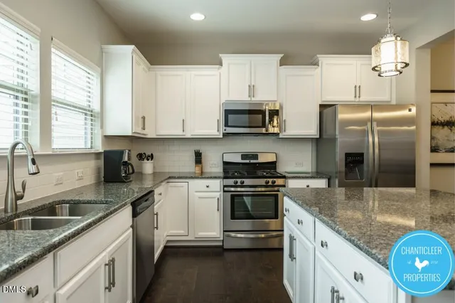 a kitchen with kitchen island granite countertop a sink stainless steel appliances and white cabinets