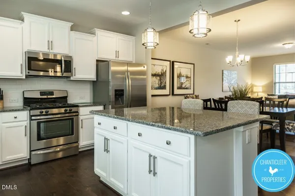 a kitchen with stainless steel appliances granite countertop a sink a stove a refrigerator cabinets and chairs