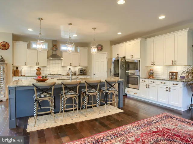 a kitchen with stainless steel appliances kitchen island granite countertop a sink a stove and cabinets
