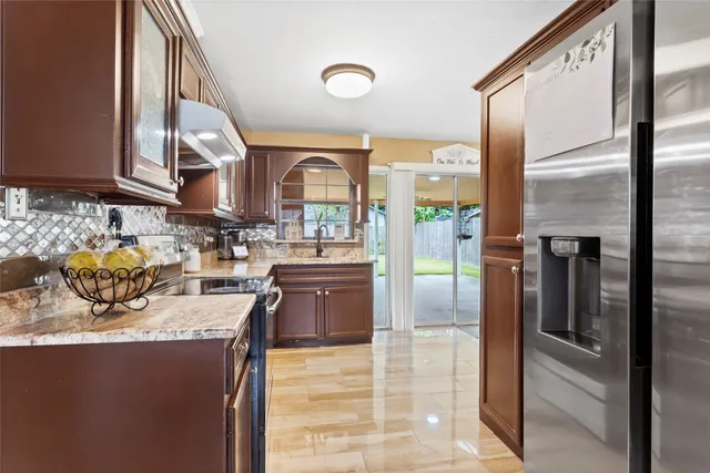 a kitchen with stainless steel appliances granite countertop a refrigerator a stove and a sink with wooden floor
