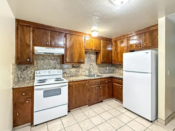a kitchen with stainless steel appliances granite countertop a refrigerator a stove and a sink