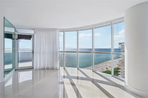 a spacious bedroom with a large window and refrigerator