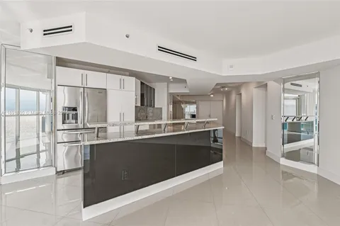a large kitchen with kitchen island a large counter top space and stainless steel appliances