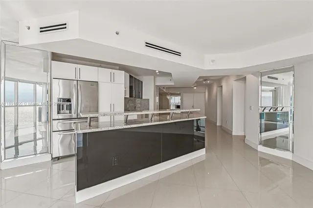 a large kitchen with kitchen island a large counter top space and stainless steel appliances