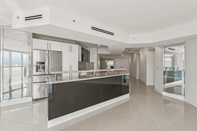 a large kitchen with kitchen island a large counter top space and stainless steel appliances