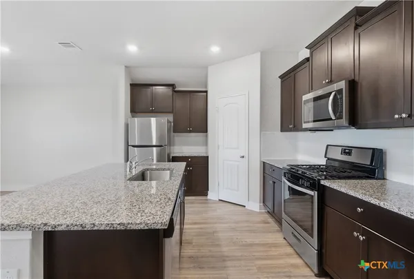 a kitchen with granite countertop kitchen island cabinets stainless steel appliances and a counter space