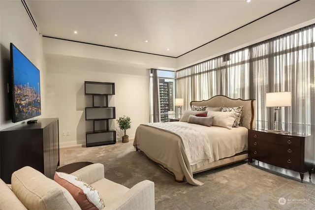 a bedroom with a bed couch and a flat tv screen