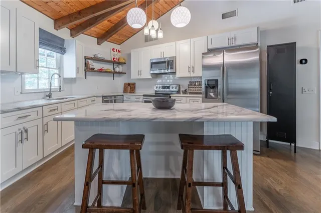 a kitchen with stainless steel appliances granite countertop a kitchen island a stove a table and chairs