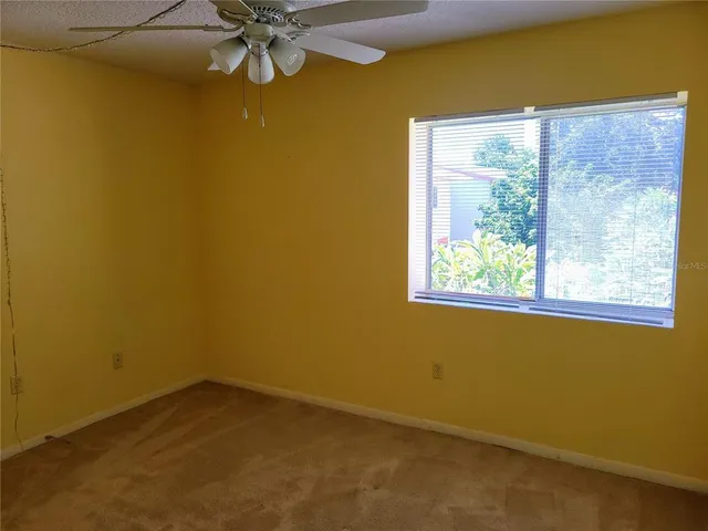 an empty room with a window and a ceiling fan