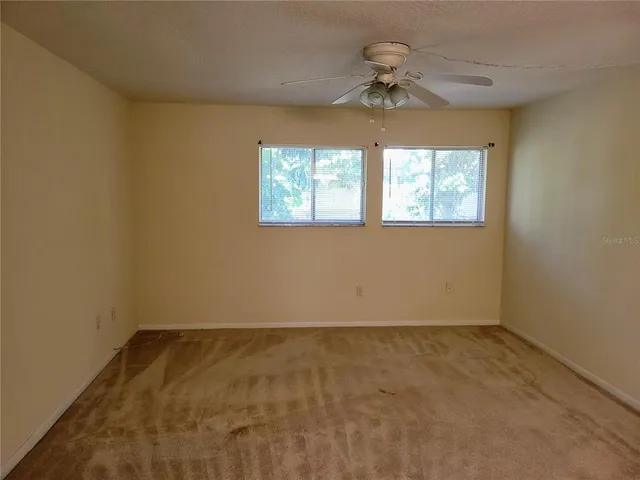 en empty room with windows and chandelier fan