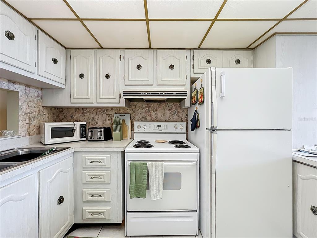 17580 Gulf Boulevard, Unit 219 Redington Shores, FL 33708 - Photo 18 of 47 a kitchen with white cabinets and white appliances