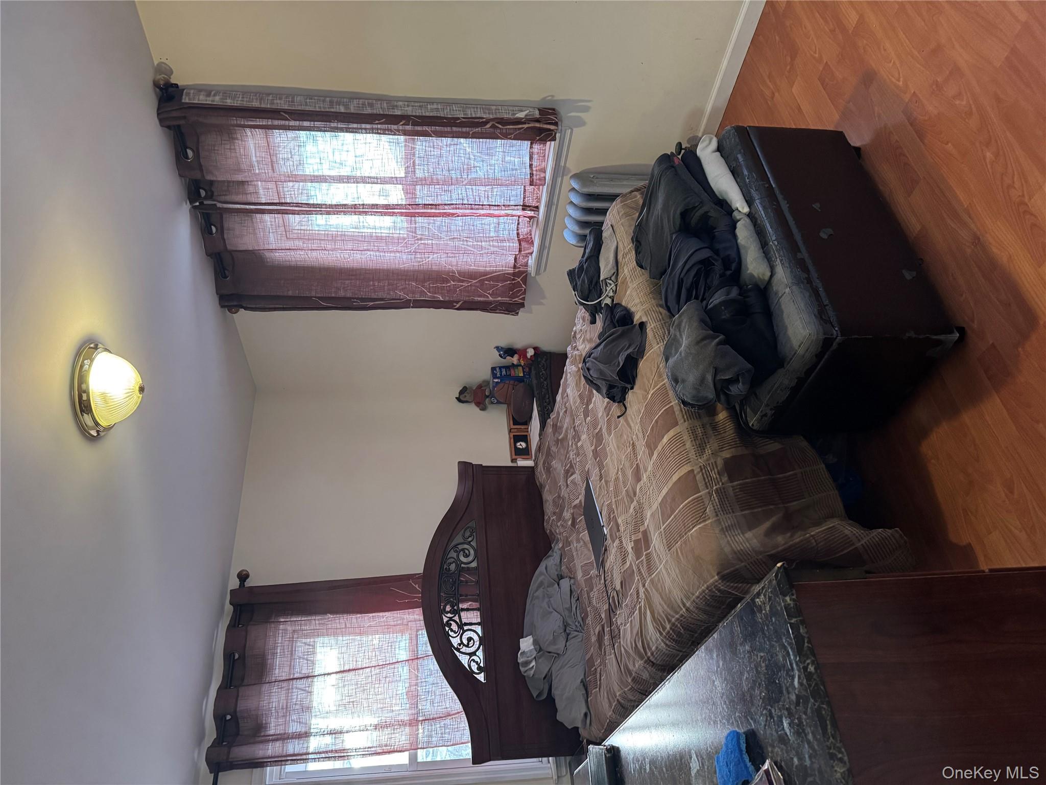 24-31 Deerfield Road Queens, NY 11691 - Photo 17 of 25 Bedroom featuring multiple windows, wood finished floors, and radiator heating unit