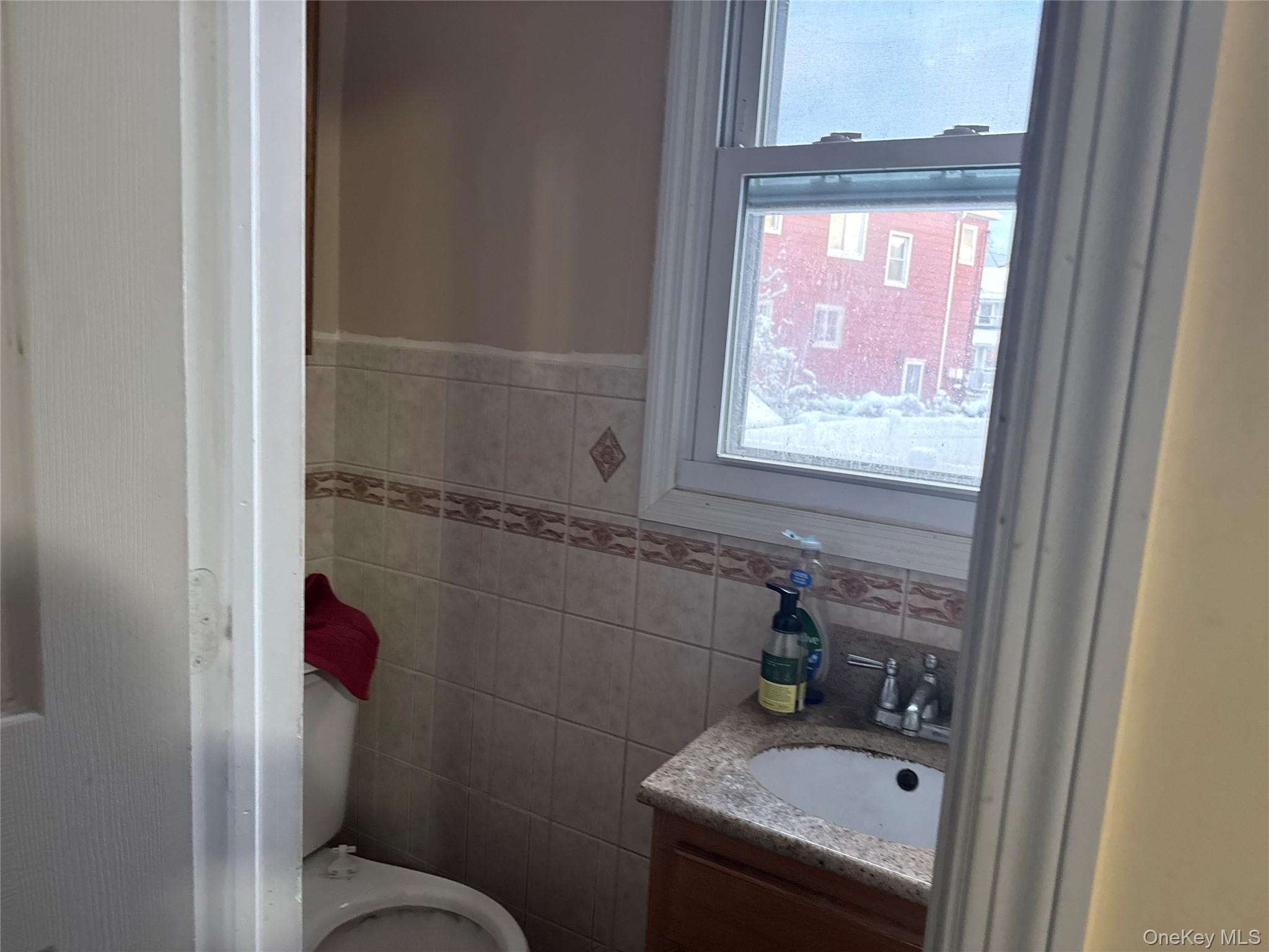 24-31 Deerfield Road Queens, NY 11691 - Photo 20 of 25 Bathroom featuring vanity, tile walls, and a wainscoted wall