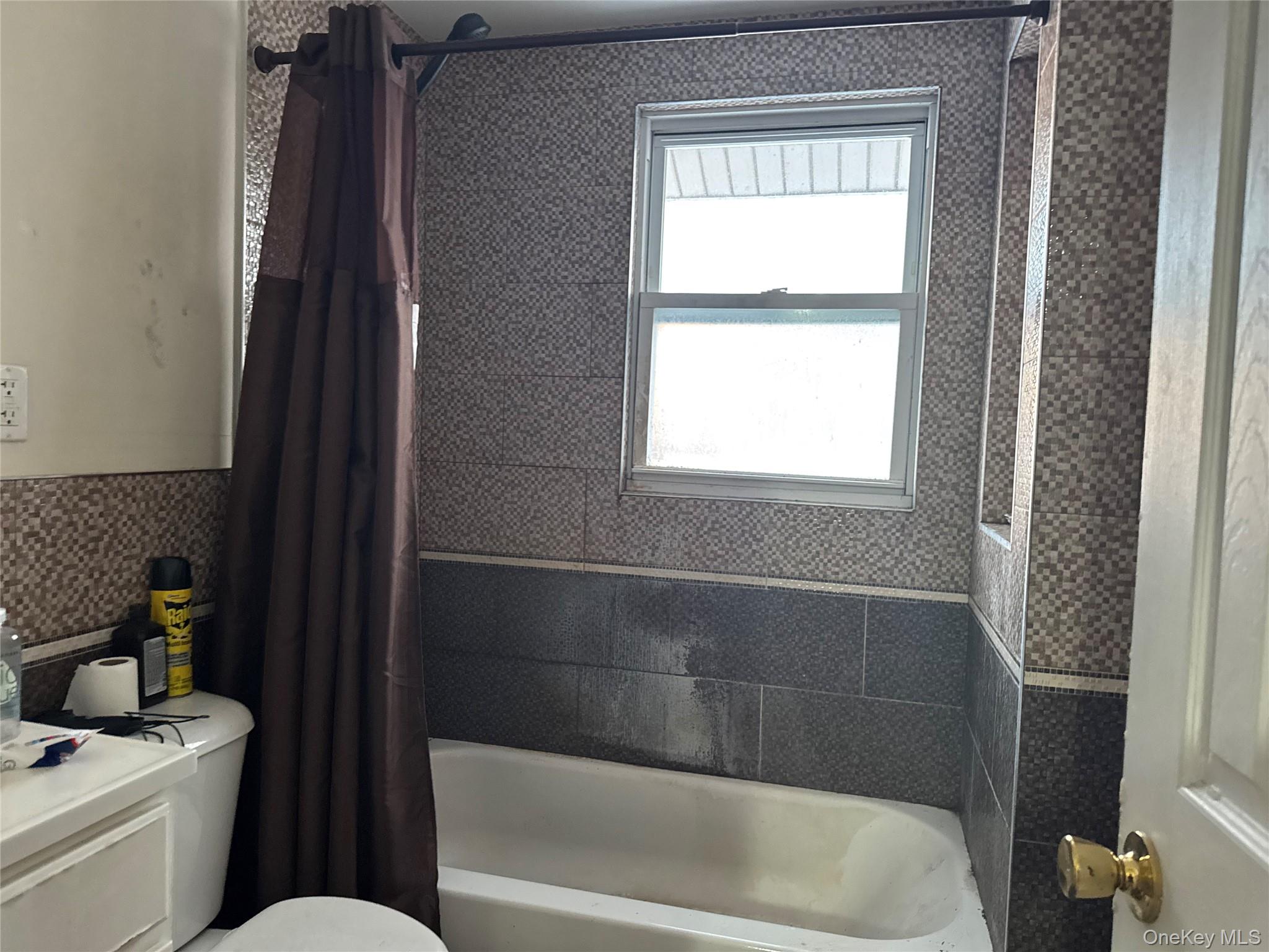 24-31 Deerfield Road Queens, NY 11691 - Photo 9 of 25 Full bathroom featuring shower / bathtub combination with curtain and toilet