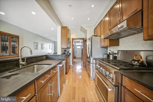a kitchen with stainless steel appliances granite countertop a sink stove and refrigerator