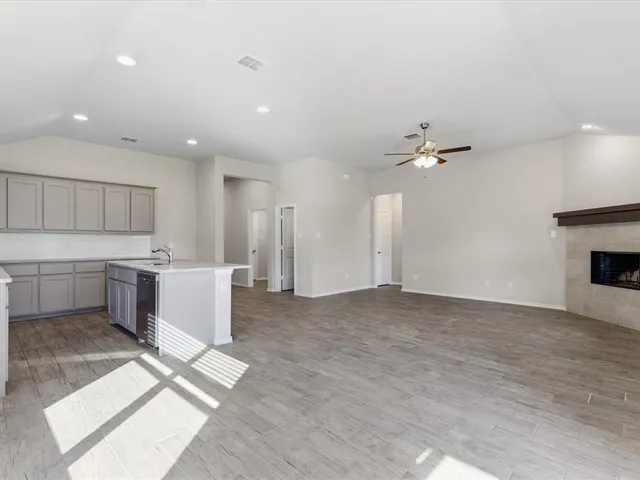 a view of a kitchen with a stove cabinets a ceiling fan and wooden floor