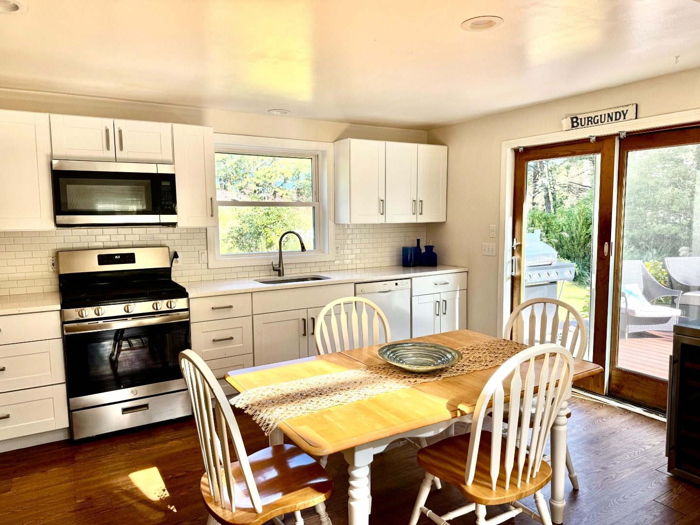 5 Seth's Path Oak Bluffs, MA 02557 - Photo 11 of 19 a kitchen with stainless steel appliances granite countertop a stove a sink a microwave a dining table and chairs with wooden floor