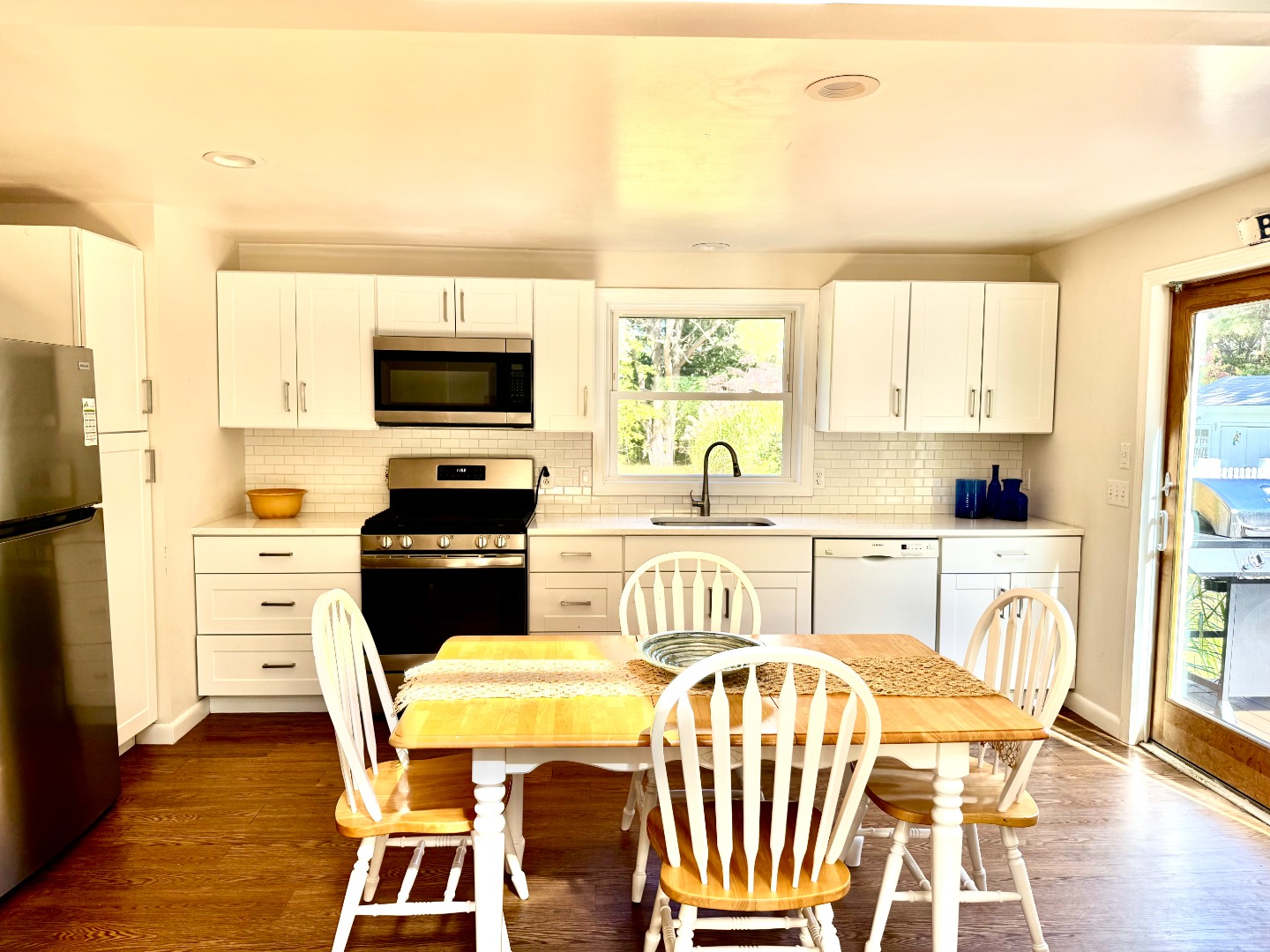 5 Seth's Path Oak Bluffs, MA 02557 - Photo 9 of 19 a kitchen with stainless steel appliances granite countertop a stove a sink a microwave a dining table and chairs with wooden floor