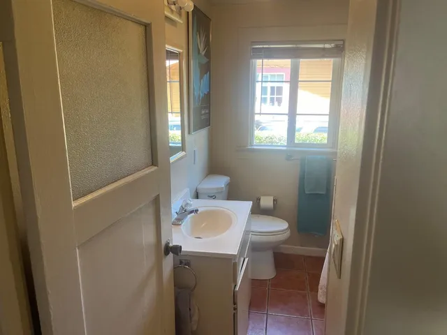 a bathroom with a granite countertop toilet a sink and a mirror