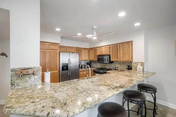 a kitchen with stainless steel appliances kitchen island granite countertop a refrigerator and cabinets