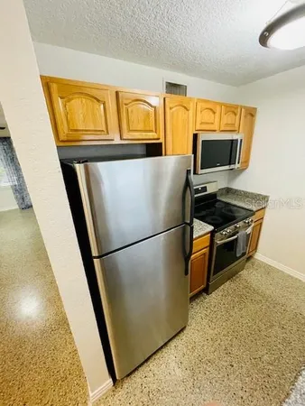 a kitchen with stainless steel appliances granite countertop a refrigerator and a stove top oven
