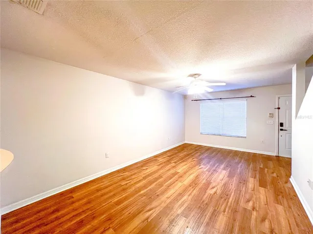 a view of empty room with wooden floor and fan