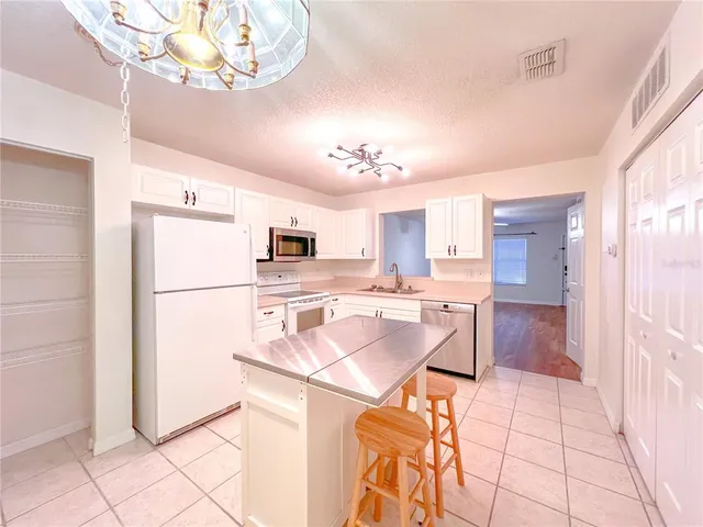 a kitchen with stainless steel appliances a refrigerator a stove a dining table and chairs