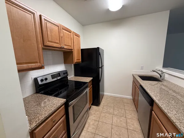 a kitchen with granite countertop a stove sink and cabinets