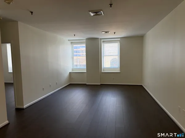 an empty room with wooden floor and windows