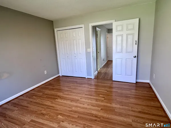 a view of an empty room with wooden floor and closet