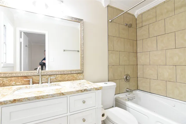 a bathroom with a granite countertop bathtub sink vanity mirror and toilet