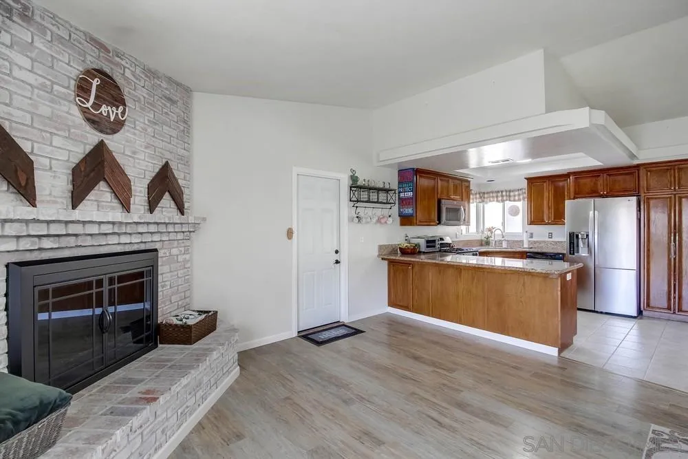 861 Peutz Valley Road Alpine, CA 91901 - Photo 12 of 42 a kitchen with stainless steel appliances granite countertop a refrigerator a stove a sink dishwasher and a fireplace with wooden floor