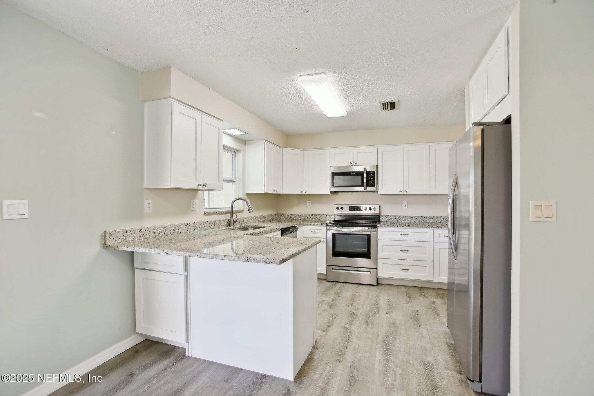 230 Lily Road St. Augustine, FL 32086 - Photo 15 of 39 a kitchen with stainless steel appliances granite countertop a stove top oven a sink dishwasher and a refrigerator with wooden floor