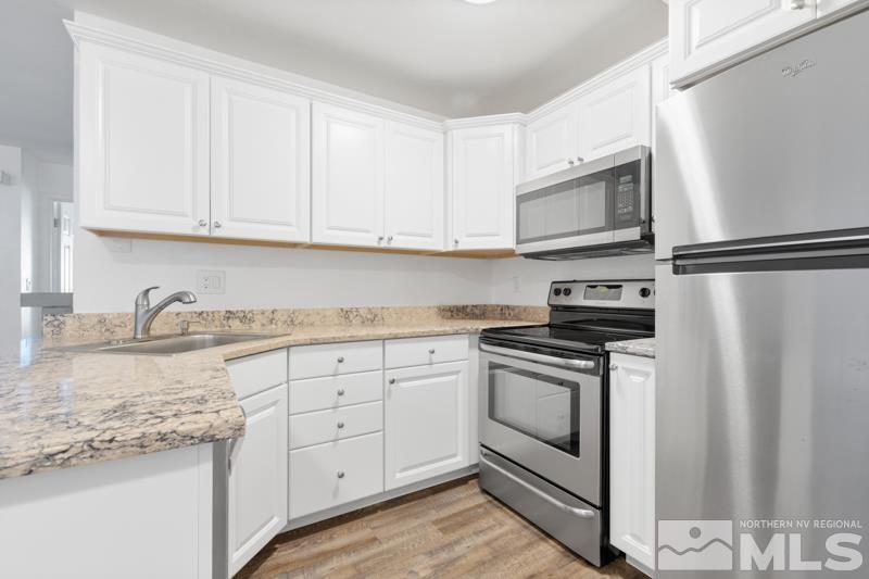 4701 Reggie Road Reno, NV 89502 - Photo 4 of 29 a kitchen with granite countertop white cabinets and white appliances