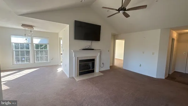 a view of a livingroom with a fireplace a ceiling fan and windows