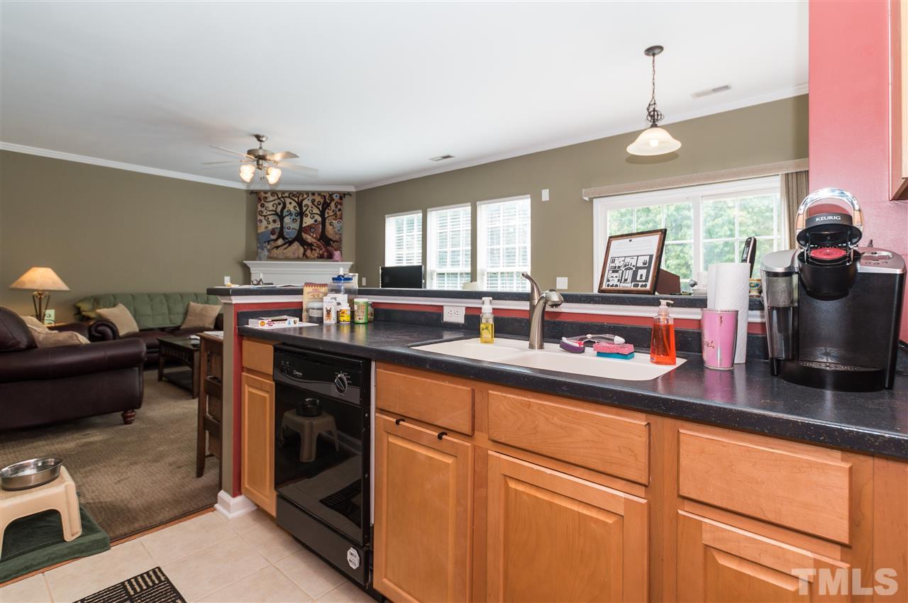 8417 Whisper Ridge Place Raleigh, NC 27613 - Photo 8 of 24 a kitchen with kitchen island granite countertop a sink cabinets and window