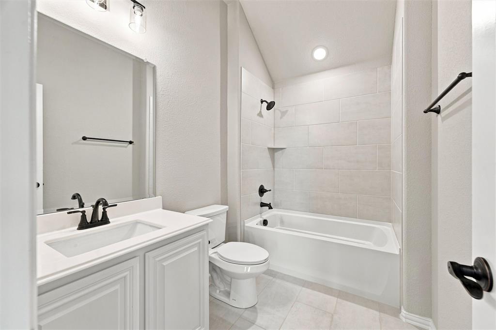 5225 Rowlan Row Midlothian, TX 76065 - Photo 28 of 33 Spa-inspired bathroom featuring a white vanity with dual sinks and matte black hardware, subway tile surround, recessed lighting, and an alcove bathtub with glass enclosure and matching matte black fixtures