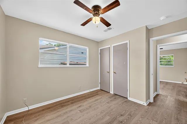 a view of an empty room with window and wooden floor