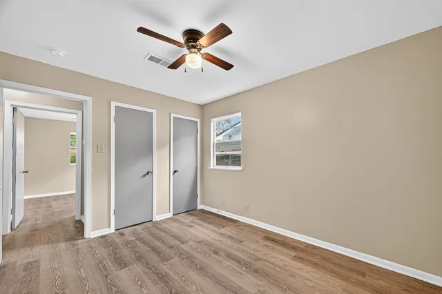 an empty room with wooden floor closet and fan