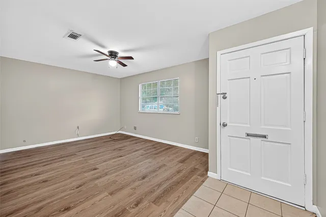 an empty room with wooden floor and ceiling fan