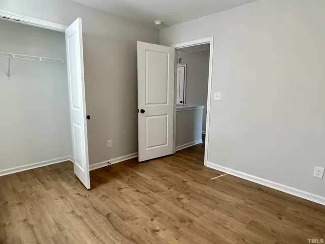 an empty room with wooden floor and closet area