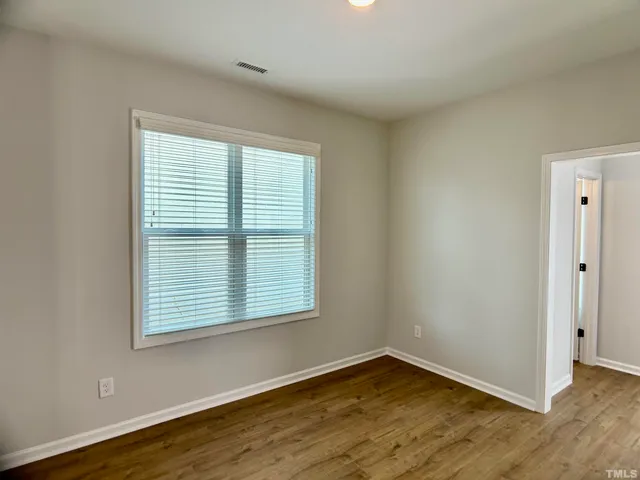 an empty room with wooden floor and a window