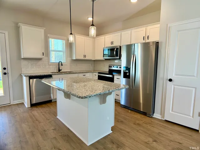 a kitchen with stainless steel appliances granite countertop a refrigerator a sink and a stove