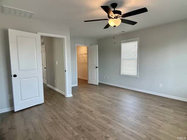 a view of an empty room with a window and wooden floor