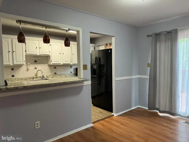 a kitchen with granite countertop a refrigerator and wooden floor